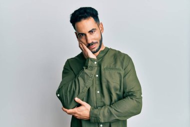 Günlük kıyafetler giyen genç İspanyol adam kollarını kavuşturarak depresyondan sıkılmış ve yorgun görünüyor.. 