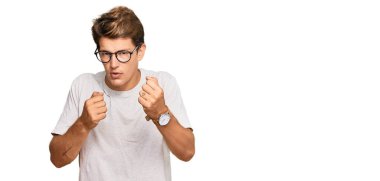 Yakışıklı beyaz adam, günlük kıyafetler ve gözlük takıyor. Yumruk savunma hareketleriyle dövüşmeye hazır. Kızgın ve üzgün. 