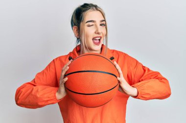 Genç modern kız basketbol topu tutuyor kameraya seksi bir ifadeyle bakıyor, neşeli ve mutlu bir yüzle.. 