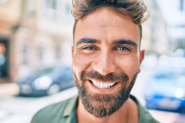 Genç İspanyol adam gülümseyerek şehirde mutlu bir şekilde yürüyor.