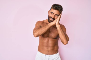 Genç İspanyol adam üstsüz uyuyor. Yorgun düşler görüyor ve elleri ile poz veriyor. Gözleri kapalı gülümsüyor.. 