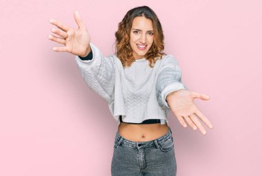 Sıradan bir kazak giyen, kollarını açıp kameraya gülümseyen beyaz bir kadın. Mutluluğu kucaklayan neşeli bir ifade.. 