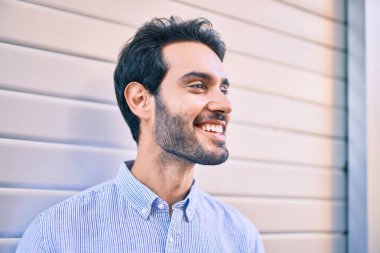 Genç İspanyol adam gülümsüyor. Mutlu bir şekilde şehrin duvarına yaslanıyor..