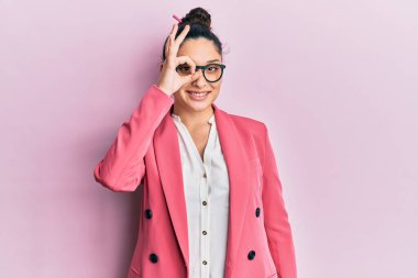 Güzel bir orta doğulu kadın iş ceketi ve gözlük takıyor. El hareketleriyle gülümsüyor, gözleriyle mutlu yüzle parmaklarının arasından bakıyor.. 