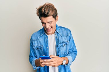 Yakışıklı beyaz adam akıllı telefon kullanıyor ve kahkahalarla gülüyor çünkü komik çılgın bir şaka.. 