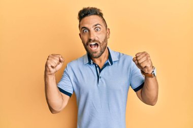 Sakallı, sıradan kıyafetler giyen yakışıklı adam kollarını kaldırıp, gözlerini açarak başarıyı kutluyor ve şaşırıyor. Kazanan konsept. 