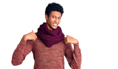 Genç Afro-Amerikan adam, günlük kışlık süveter ve eşarp giyiyor. Kendine güvenen, gülümseyen, kendini gururlu ve mutlu gösteren biri.. 