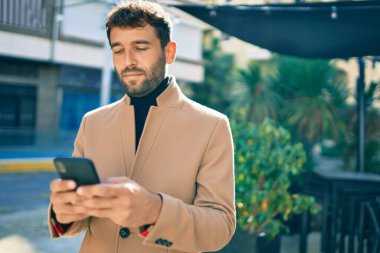 Zarif ceketli yakışıklı bir iş adamı. Açık havada akıllı telefon kullanıyor.