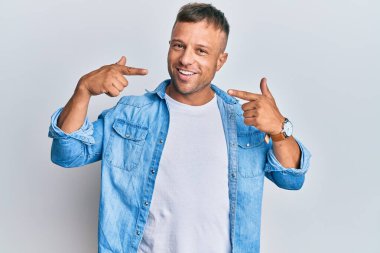 Sıradan kot ceket giyen yakışıklı kaslı adam gülümseyen, parmaklarıyla ve ağzıyla işaret eden. diş sağlığı kavramı. 