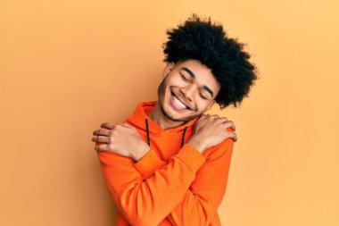 Afro saçlı, sıradan bir kazak giyen, mutlu, pozitif ve kendinden emin gülümseyen Afro-Amerikalı genç bir adam. Sevgi ve özgüven. 