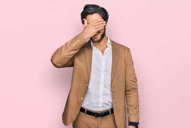 İş kıyafetleri giymiş, gülümseyen ve gülen genç İspanyol adam şaşırtmak için gözlerini kapatıyor. kör kavram. 