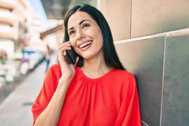 Genç Latin kız gülümsüyor. Şehirdeki akıllı telefondan konuşuyor..