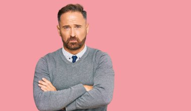 İş kıyafetleri giyen, yakışıklı, kuşkucu ve gergin kolları çaprazlanmış bir yüz ifadesi takınan orta yaşlı bir adam. negatif kişi. 