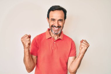 Orta yaşlı İspanyol bir adam gündelik giysiler giyip kollarını kaldırıp, gözleri açık bir şekilde başarıyı kutluyor. Kazanan konsept. 