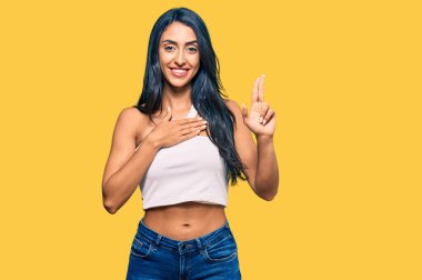 Güzel İspanyol kadın gündelik kıyafetler giyip gülümsüyor. Göğsü ve parmakları havada küfür ediyor. Sadakat yemini ediyor. 