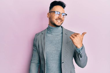 İş kıyafetleri giymiş genç bir Arap, baş parmağını yana kaldırmış, ağzı açık gülümsüyor. 