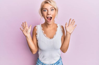 Sıradan kıyafetler giyen genç sarışın kız çılgın ve başarıyı kollarını kaldırıp heyecanla haykırarak kutluyor. Kazanan konsept 