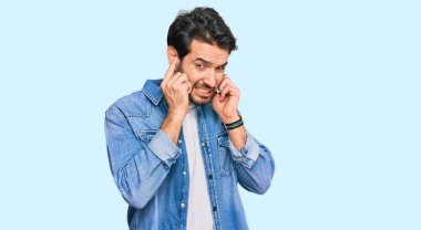 Gürültülü müzik sesi için günlük kıyafetler giyen genç İspanyol adam kulaklarını parmaklarıyla kapatıyor. sağır kavramı. 