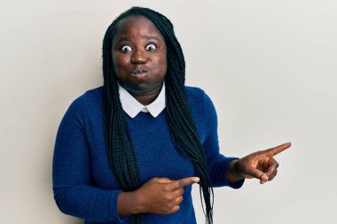 Saçları örgülü, yanaklarını şişiren komik yüzlü genç siyahi bir kadın. Ağzı havayla şişer, havayı yakalar.. 