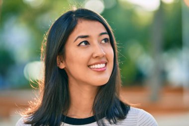 Genç İspanyol kadın gülümseyerek parkta mutlu bir şekilde yürüyor.