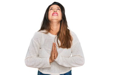 Güzel İspanyol kadın gündelik süveter giyip elleri bağlı yalvarıyor ve dua ediyor. Yüzünde umut ifadesi var. Çok duygusal ve endişeli. Yalvarıyor. 