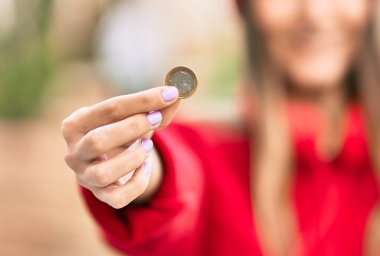 Şehirde yün şapka takan genç İspanyol kadın 1 avro para tutuyor..