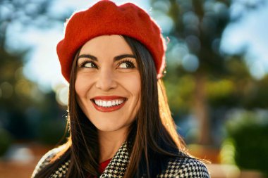 Genç İspanyol kadın gülümseyerek şehirde mutlu mesut dikiliyor..