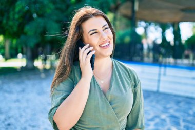 Genç İspanyol kadın gülümsüyor. Şehrin caddesinde yürüyen akıllı telefonla konuşuyor.