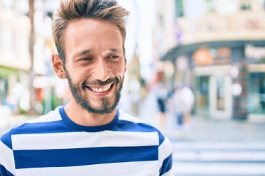 Sakallı yakışıklı beyaz adam, dışarıda mutlu bir şekilde gülümsüyor.