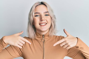 Gündelik kıyafetler giyen, kendine güvenen, gülümseyen, kendini gururlu ve mutlu gösteren genç sarışın kız.. 