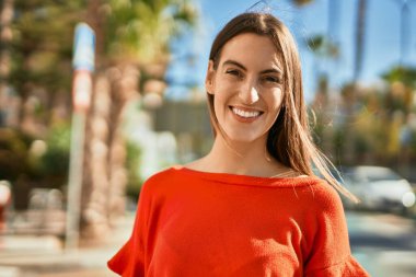 Genç İspanyol kadın gülümseyerek şehirde mutlu mesut dikiliyor..