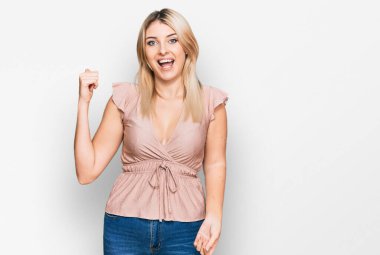 Gündelik kıyafetler giyen, mutlu yüzlü gülümseyen ve baş parmağıyla yan tarafı gösteren beyaz bir kadın.. 