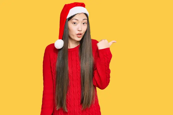 若い中国人女性を身に着けているクリスマスの帽子驚くべきポインティングとともに手指で側面に オープン口驚きの式 — ストック写真