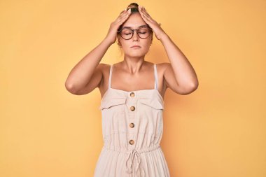 Yazlık elbise giyen beyaz güzel bir kadın baş ağrısı çekiyor. Acı ve migren yüzünden çaresiz ve stresli. Eller başının üstünde.. 