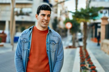 Genç İspanyol adam gülümseyerek şehirde mutlu mesut dikiliyor..