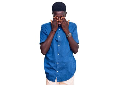 Genç Afro-Amerikan adam günlük kıyafetler giyiyor yorgunluk ve baş ağrısı için gözlerini ovuşturuyor, uykulu ve yorgun bir ifade takınıyor. görme sorunu 