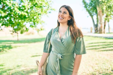 Genç İspanyol kadın gülümseyerek parkta mutlu bir şekilde yürüyor.