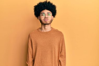 Afro saçlı, kışlık süveter giyen, komik suratlı Afro Amerikalı genç bir adam. Havayla şişmiş ağız, çılgın bir ifade.. 