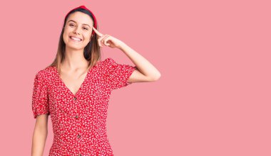 Elbise ve diyabet giymiş güzel bir kız tek parmakla başını işaret ediyor, harika bir fikir ya da düşünce, iyi bir hafıza. 