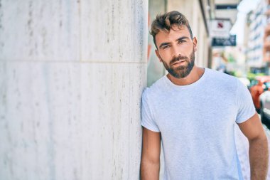 Genç İspanyol adam gülümsüyor. Mutlu bir şekilde şehrin duvarına yaslanıyor.