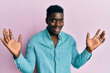 Yakışıklı siyah adam sıradan kıyafetler giyip çılgınlığı kutluyor ve başarıya hayret ediyor kolları açık ve gözleri açık heyecanla bağırıyor. Kazanan konsept 