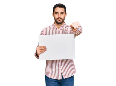 Elinde boş pankart tutan genç İspanyol adam kamerayı işaret ediyor ve sen kendine güvenen ciddi bir hareket yapıyorsun. 
