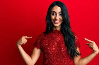 Güzel İspanyol kadın kırmızı arka planda şık kıyafetler giyiyor. Kendine güvenen, yüzünde gülümseme olan, kendini gururlu ve mutlu bir şekilde gösteren.. 