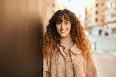 Genç İspanyol kadın gülümseyerek şehirde mutlu mesut dikiliyor.