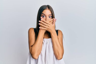 Gündelik kıyafetler giyen genç İspanyol kadın yanlışlıkla elleri ile ağzını kapatırken şok oldu. gizli kavram. 
