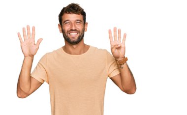 Sakallı, sıradan tişörtlü yakışıklı genç adam dokuz numarayı gösteriyor ve gülümsüyor. Kendinden emin ve mutlu.. 