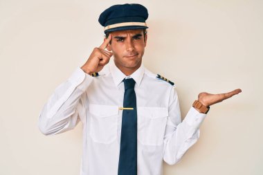 Uçak pilotu üniforması giyen genç İspanyol adam avuç içinin açık olmasından rahatsız ve kafası karışmış bir şekilde fotokopi alanını gösteriyor ve alnını işaret ediyor. Bunu bir düşün.. 