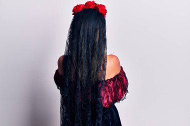 Ölü makyajlı bir Meksika günü giymiş genç bir kadın kollarını kavuşturup arkasına bakıyor. 