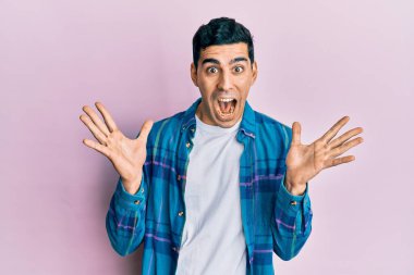 Yakışıklı İspanyol bir adam sıradan kıyafetler giyip çılgınlığı kutluyor ve başarıya hayret ediyor kolları açık ve gözleri açık heyecanla bağırıyor. Kazanan konsept 