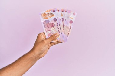 İspanyol eli 50 Meksika Pezosu 'nu soyutlanmış pembe arka planda tutuyor..